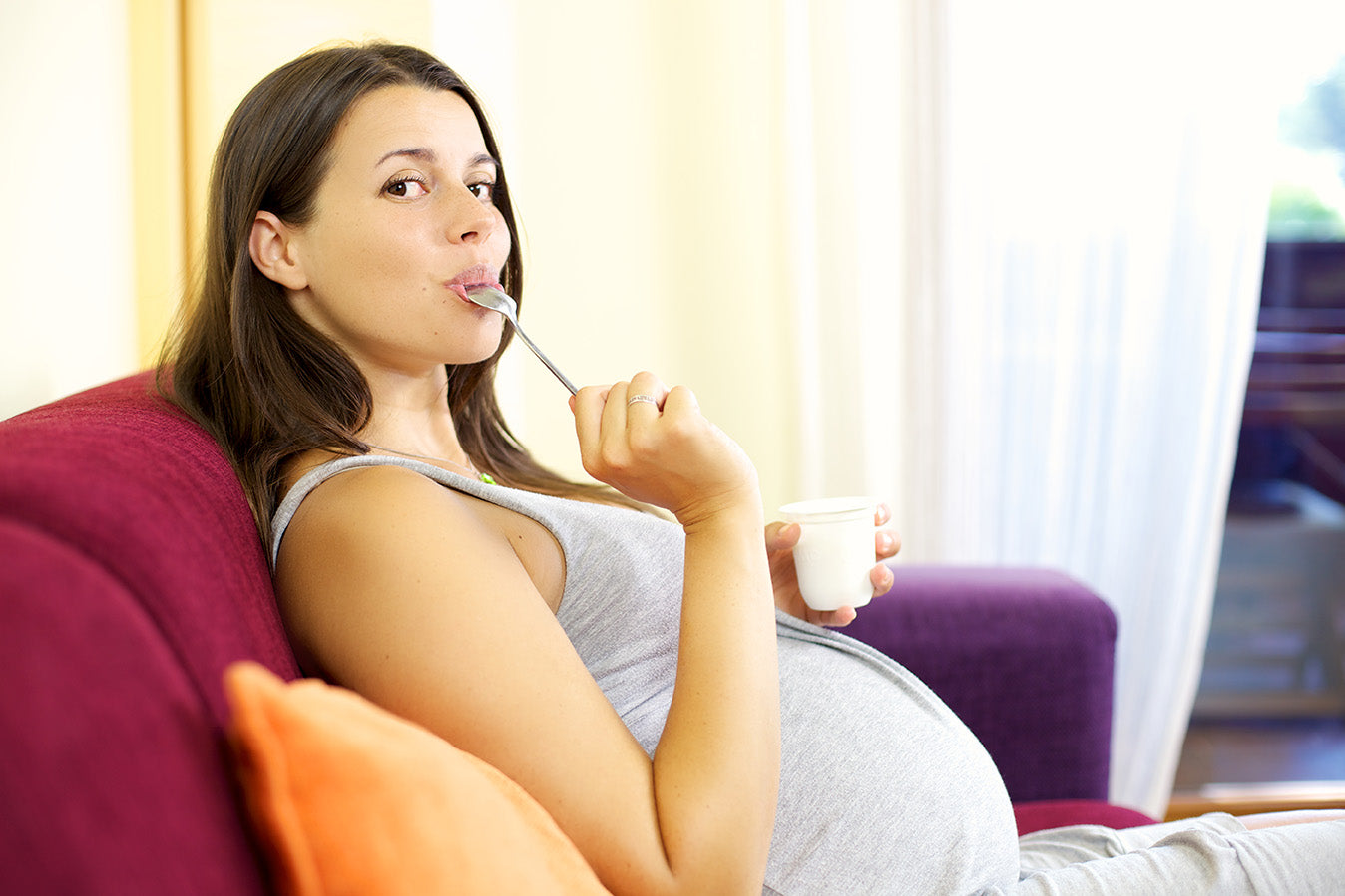 Food & Diet During Pregnancy. Pregnant woman eating yogurt sitting down, Nutritional basics